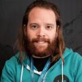 Michael Schmid profile image: man with brown long hair and beard wearing a green zipper hoodie